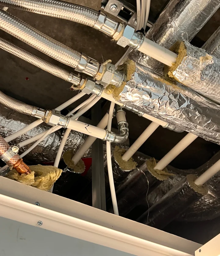 Site survey photograph of existing pipework and connections above an office ceiling